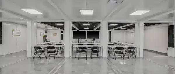 Modern conference room with long tables, foldable chairs, and bright lighting, perfect for meetings.