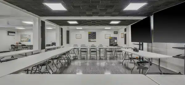Modern conference room with U-shaped table setup and large screens on walls