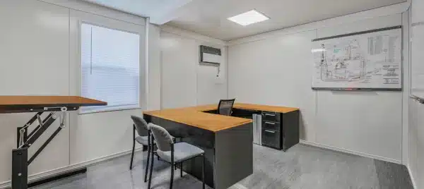 Modern office space with desks, chairs, and a whiteboard in a clean, well-lit room.