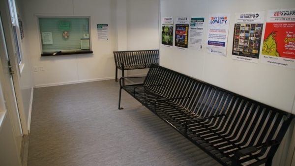Small waiting area with metal benches and colorful posters on the wall