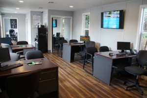 Modern office with wooden floors and multiple workstations featuring computers and chairs.